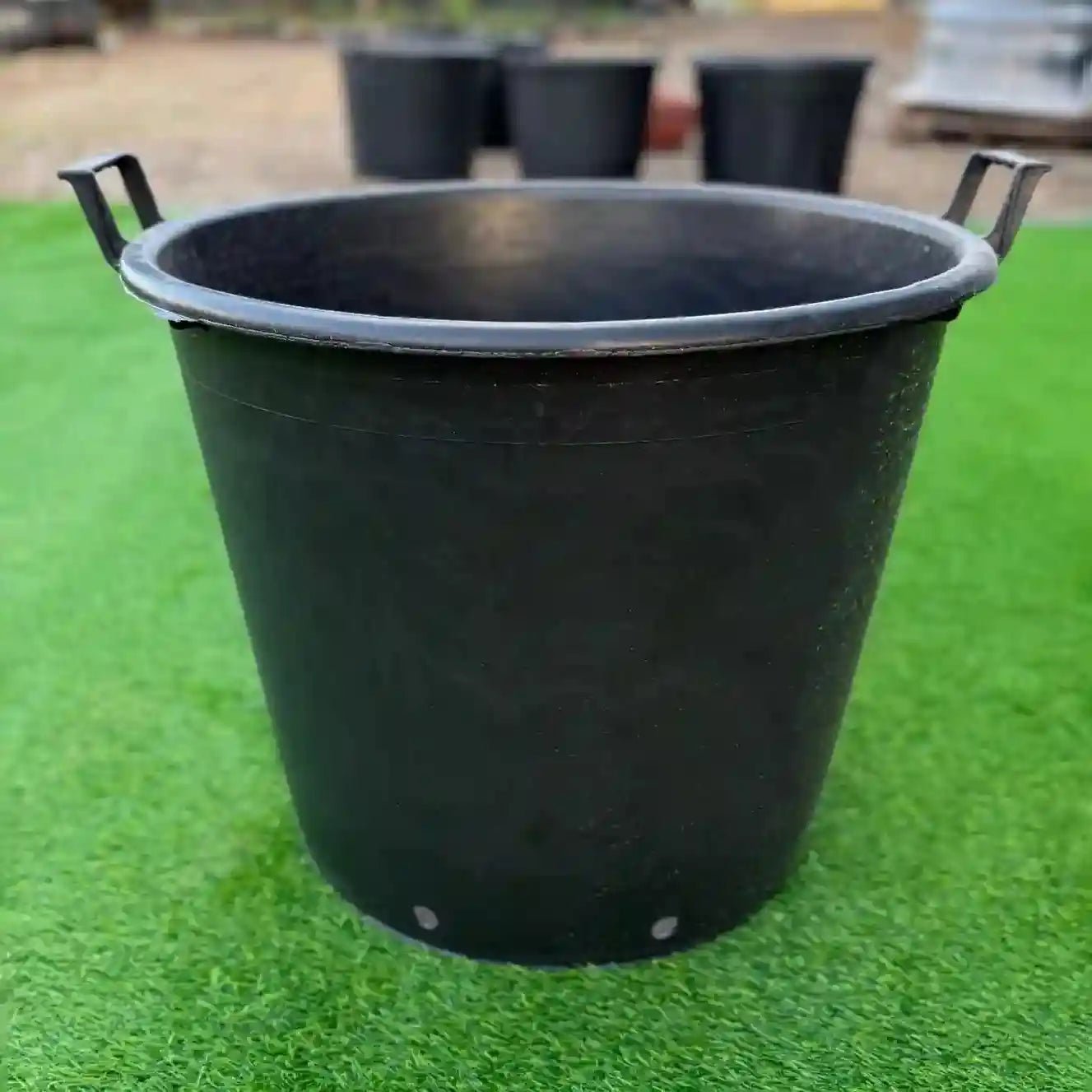 Black plastic bucket on a green grassy surface