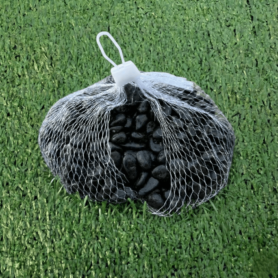 Bag of black stones in a mesh bag on green grass