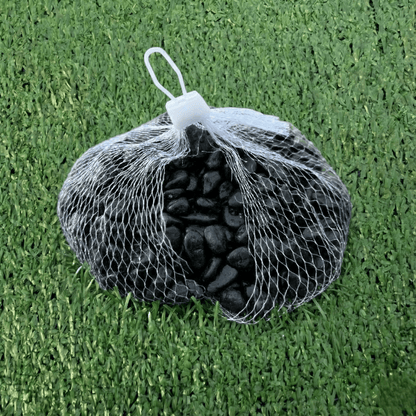 Bag of black stones in a mesh bag on green grass