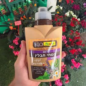 Hand holding a bottle labeled 'BIO' with flowers in the background