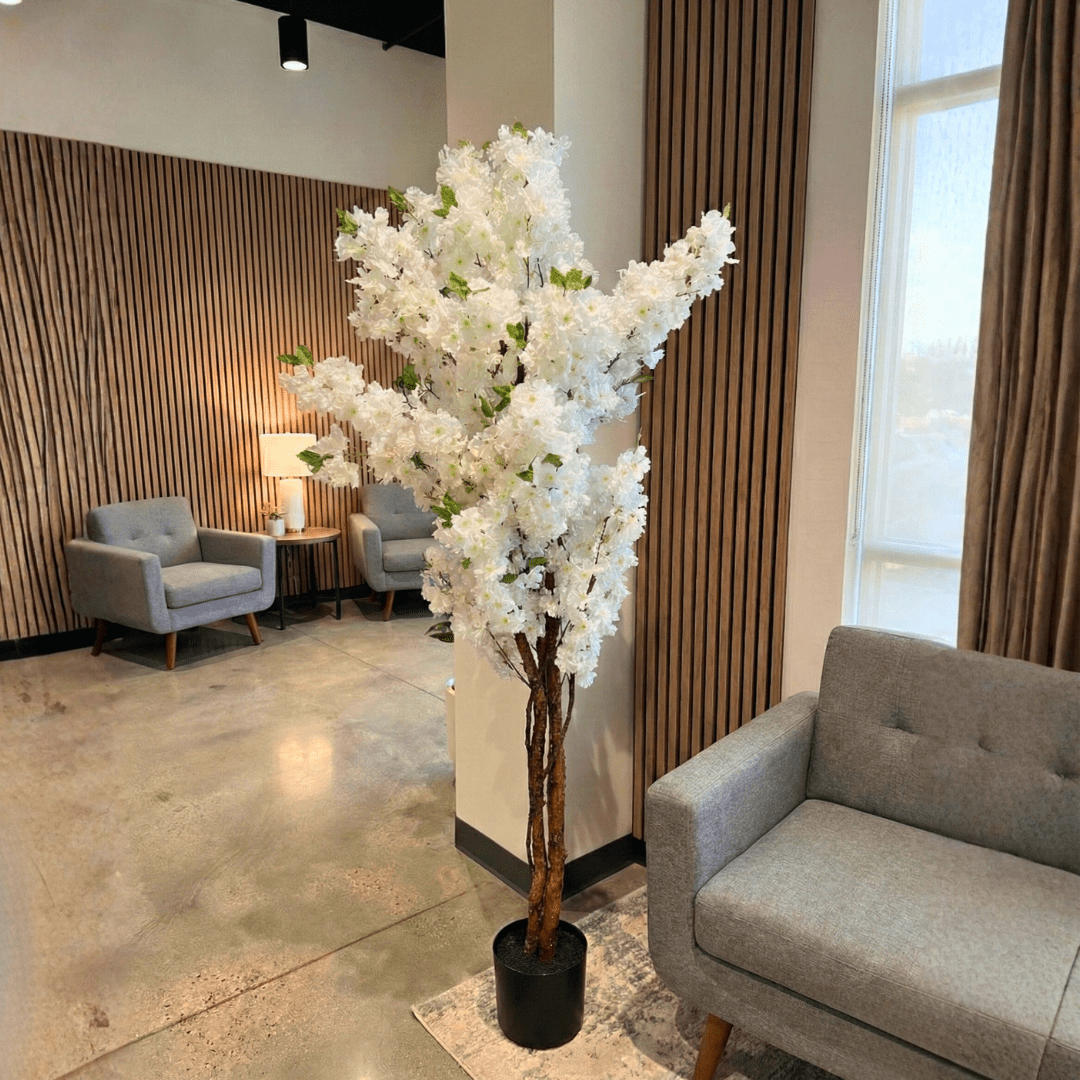 Decorative white floral tree in a room with gray chairs and a lamp.