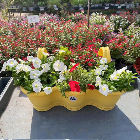 Yellow wavy planter with flowers in a garden setting