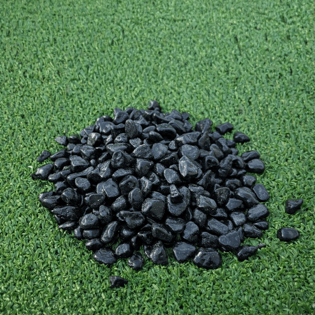 Pile of black pebbles on green artificial grass