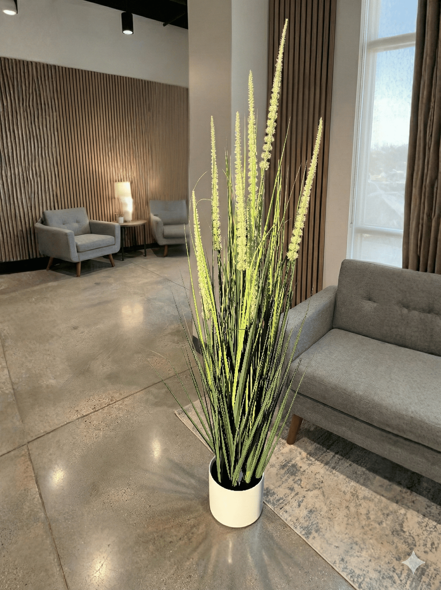 artifical plant in a white pot in a modern office setting with gray furniture and large windows.
