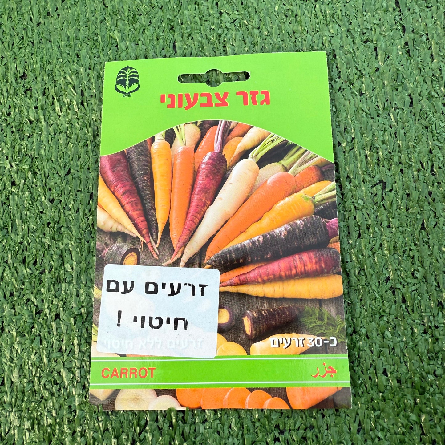 חפיסת זרעי גזר צבעוני ברקע של דשא סינטטי ירוק